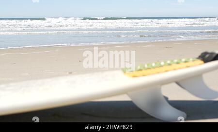 Surfboard per il surf sdraiato sulla spiaggia di sabbia, costa californiana, USA. Onde oceaniche e tavole da surf bianche o paddleboard. Longboard o sup per la ricreazione di sport acquatici con acqua di mare. Cinematografia senza giunture. Foto Stock