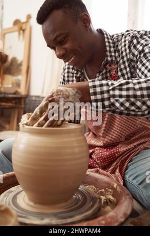 Gioioso ceramista concentrato giovane gettando vaso di argilla Foto Stock