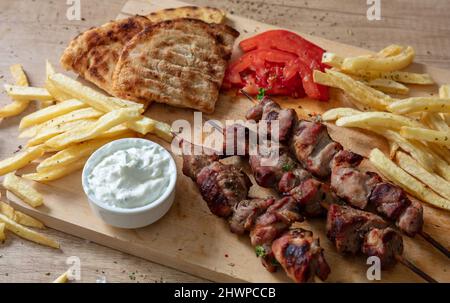Piatto souvlaki, cibo di carne greca. Spiedini alla griglia e pita pane su tavola di legno, da vicino sopra vista, Foto Stock