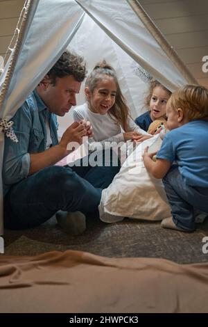 Sorridenti ragazze e fratello che trascorrono del tempo insieme al padre Foto Stock