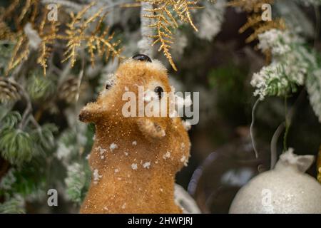 Scoiattolo afferra ramo conifere in inverno. Lo scoiattolo giocattolo scorre attraverso i boschi. Gnaws animale sul ramoscello. Figurine per Natale. Roditore con capelli rossi. Foto Stock