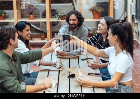 Felici uomini d'affari e donne d'affari che tostano bevande alla caffetteria Foto Stock