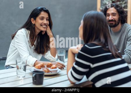 Donna d'affari sorridente e colleghi che hanno brunch presso la caffetteria dell'ufficio Foto Stock