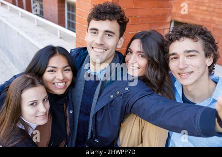 Sorridenti amici multirazziali che prendono selfie al campus universitario Foto Stock