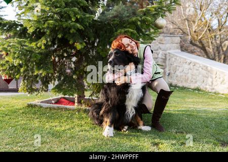 Donna felice che abbraccia il cane in cortile a Natale Foto Stock