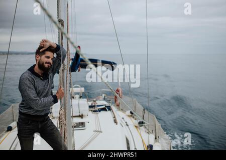 Uomo pensieroso appoggiato su albero di barca a vela nel Mar Mediterraneo Foto Stock