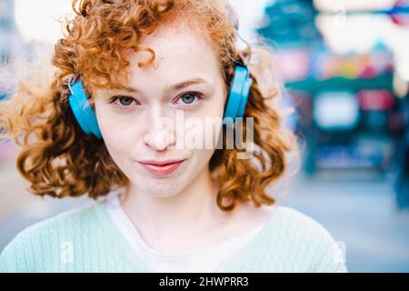 Giovane donna ascoltando la musica attraverso le cuffie Foto Stock