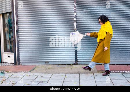 Giovane donna che cammina con bottiglie di plastica in sacchetto di rete sul sentiero Foto Stock