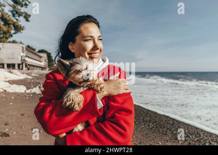 Donna felice con il cane in spiaggia Foto Stock