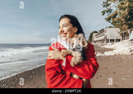 Donna felice con Yorkshire terrier in spiaggia Foto Stock