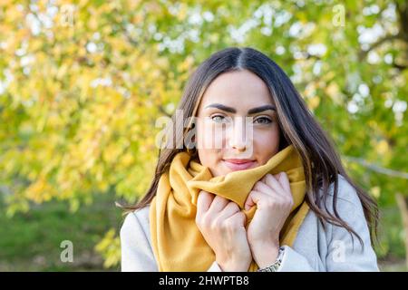 Bella giovane donna con sciarpa gialla nel parco autunnale Foto Stock