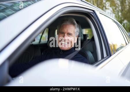 Uomo anziano felice seduto in macchina Foto Stock
