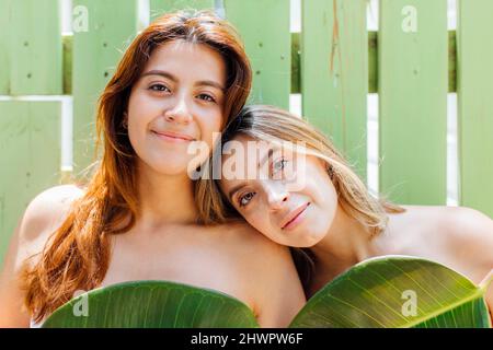 Giovane donna appoggiata alla testa sulla spalla della sorella davanti al muro Foto Stock