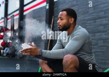 L'atleta spolverizza la polvere di gesso sulle mani in palestra Foto Stock