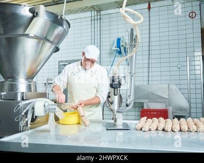 Macelleria che fa salsicce fresche con macchinari in fabbrica Foto Stock