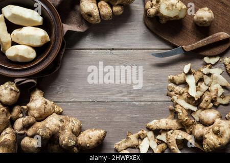 Topinambur Artichoke e coltello su tavola di legno Foto Stock
