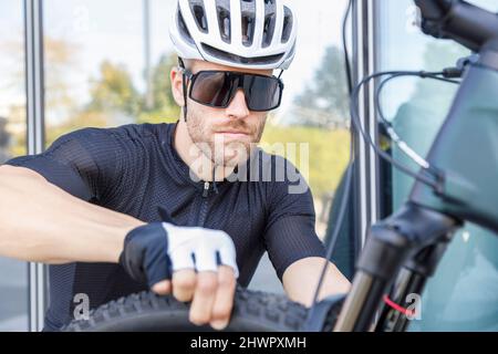 Giovane uomo che indossa occhiali da sole e casco di controllo pneumatico Foto Stock