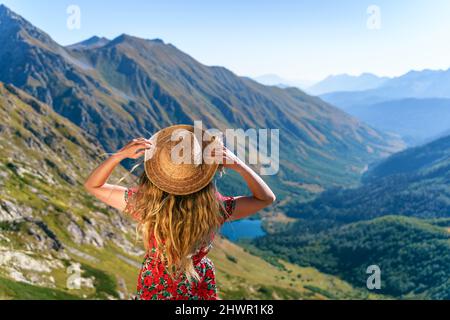 Donna con cappello di paglia che guarda le montagne del Caucaso in giornata di sole, Sochi, Russia Foto Stock