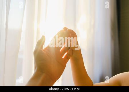 Ragazzo che tocca la mano della madre davanti al sipario a casa Foto Stock