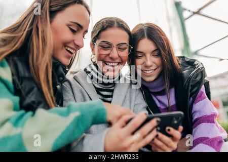 I giovani amici ridono e guardano lo smartphone Foto Stock