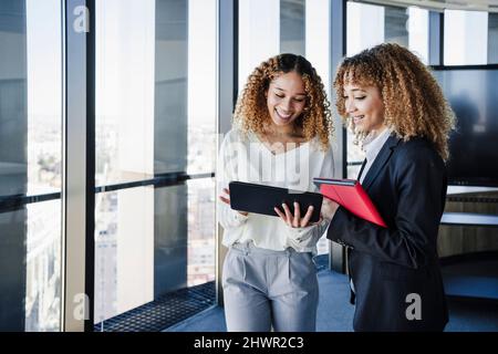 Giovani donne d'affari che condividono un tablet PC in ufficio Foto Stock