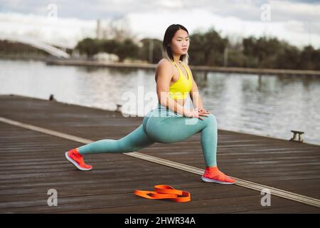 Il giovane atleta che fa l'esercitazione di riscaldamento sul jetty al lago Foto Stock