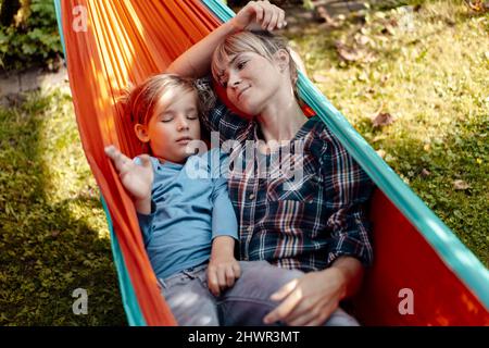 Madre che guarda il figlio che dorme in amaca Foto Stock