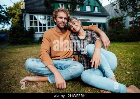 Coppia seduta insieme a terra in giardino Foto Stock
