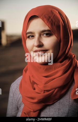 Giovane donna sorridente che indossa hijab rosso Foto Stock
