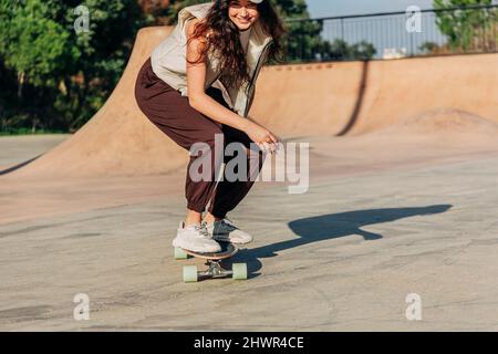 Skateboard donna sulla rampa sportiva nel parco Foto Stock