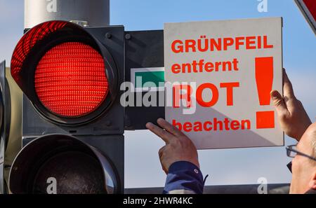 Lipsia, Germania. 07th Mar 2022. Un dipendente dell'Ufficio di Ingegneria civile e del traffico appende un cartello su una freccia verde accanto a un semaforo rosso all'incrocio Adenauerallee/Rohrteichstraße. Per aumentare la sicurezza del traffico, nelle prossime settimane saranno rimosse 24 frecce verdi dai semafori di Lipsia. Negli ultimi tre anni vi sono stati diversi incidenti tra le auto che si accerteranno di rosso e che attraversano pedoni e ciclisti. Alcune delle persone coinvolte sono state gravemente ferite. Credit: Jan Woitas/dpa-Zentralbild/ZB/dpa/Alamy Live News Foto Stock