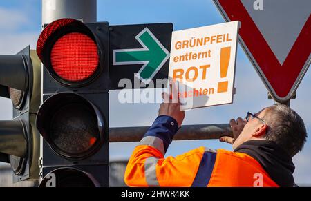 Lipsia, Germania. 07th Mar 2022. Un dipendente dell'Ufficio di Ingegneria civile e del traffico appende un cartello su una freccia verde accanto a un semaforo rosso all'incrocio Adenauerallee/Rohrteichstraße. Per aumentare la sicurezza del traffico, nelle prossime settimane saranno rimosse 24 frecce verdi dai semafori di Lipsia. Negli ultimi tre anni vi sono stati diversi incidenti tra le auto che si accerteranno di rosso e che attraversano pedoni e ciclisti. Alcune delle persone coinvolte sono state gravemente ferite. Credit: Jan Woitas/dpa-Zentralbild/ZB/dpa/Alamy Live News Foto Stock