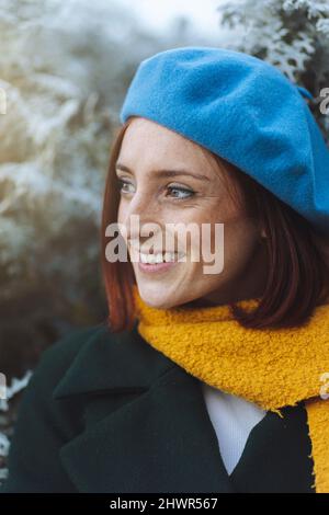 Felice donna rossa in berretto blu e sciarpa gialla Foto Stock