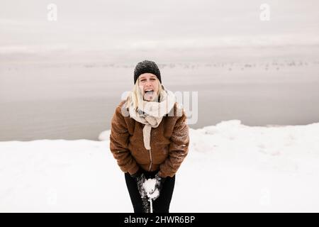 Donna spensierata in abiti caldi che grida in inverno Foto Stock