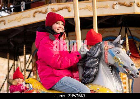 Sorridente ragazza che si gode giro a carosello al mercatino di Natale Foto Stock