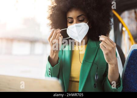 Pendolari indossare maschera protettiva viso e viaggiare in tram Foto Stock