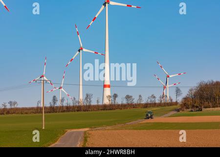 Una strada sterrata attraverso campi e vigneti porta a molte turbine eoliche Foto Stock