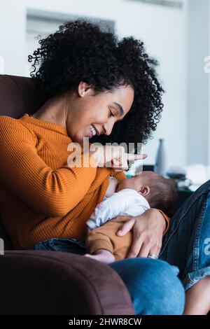 Madre che allatta il bambino nel soggiorno di casa Foto Stock