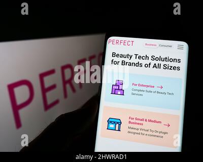 Persona che tiene il cellulare con pagina web della società taiwanese di bellezza tecnologia Perfect Corp. Sullo schermo di fronte al logo. Concentrarsi sul centro del display del telefono. Foto Stock