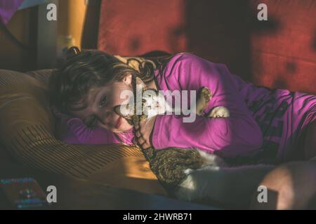 adorabile ragazza bionda rilassante al coperto con gatto incantevole Foto Stock