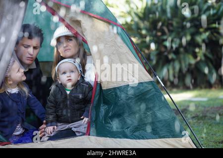 OH no, la sua pioggia. La giovane famiglia si è bloccata nella loro tenda durante una giornata piovosa. Foto Stock