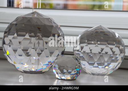 Tre ornamenti di cristallo chiaro di dimensioni diverse su una davanzale / sporgenza della finestra Foto Stock