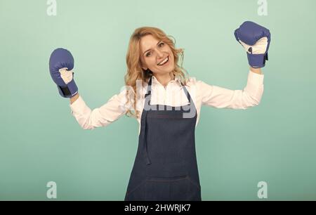 donna felice riuscito in grembiule di cuoco e guanti di boxe, casalinga Foto Stock