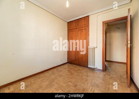 camera vuota con armadio a muro con porte in legno scuro e pavimento in parquet di quercia Foto Stock