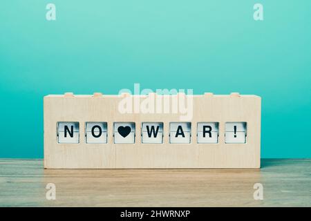 il testo non guerra in un rustico legno split flap board, su una superficie di legno contro uno sfondo blu Foto Stock