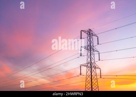 Una vista ad angolo basso di un traliccio metallico di elettricità che trasporta i fili con le grandi quantità di energia per fornire il commercio e le case con l'energia e lo spazio di copia Foto Stock