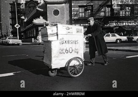 Un uomo ebreo più anziano che vende le nishes da un carro portatile, riscaldato a tre ruote. A Chinatown, Manhattan, circa 1975. Foto Stock