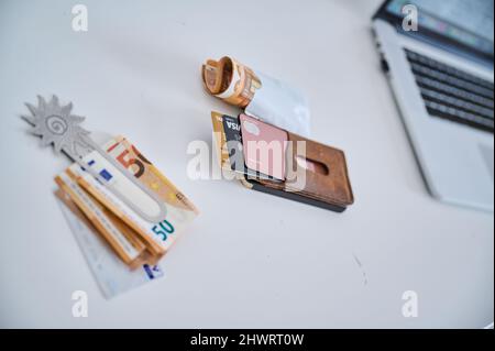 Berlino, Germania. 05th Mar 2022. Una clip di denaro femminile con bollette da 50 euro e una carta conto corrente si trova accanto a un astuccio in pelle con diverse carte di credito e un pacchetto di bollette da 50 euro. Le donne in Germania hanno continuato a guadagnare in media meno degli uomini nel 2021. Il divario di reddito, il cosiddetto divario retributivo di genere, è rimasto invariato rispetto all'anno precedente, attestandosi al 18%. Tale calcolo è stato effettuato dall'Ufficio federale di statistica. Credit: Annette Riedl/dpa/Alamy Live News Foto Stock