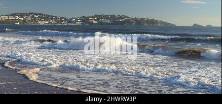 Ondate di schiuma sulla spiaggia di Preston a Paignton, nel Devon meridionale, guardando verso Torquay. Foto Stock