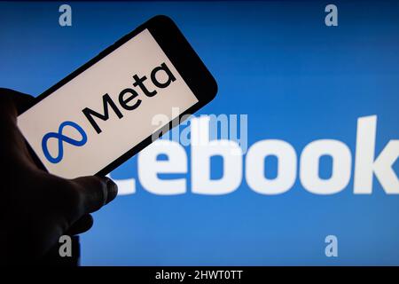 Rheinbach, Germania 30 ottobre 2021, il logo del marchio 'Meta' sul display di uno smartphone di fronte al logo Facebook.Facebook cambia nome Foto Stock